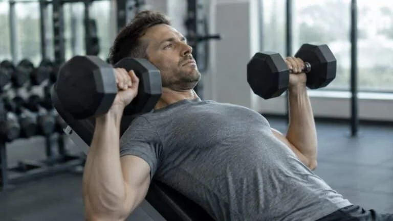Man doing an incline dumbbell chest press in a gym, training the pectoral muscles