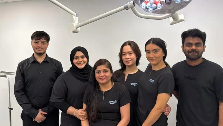 Six members of the Centre for Surgery clinical team standing beneath the operating theatre light at the Baker Street hospital in London