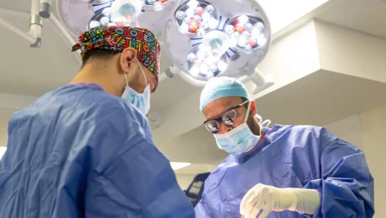 Two surgeons in gowns and masks operating under theatre lights at Centre for Surgery, Baker Street, London